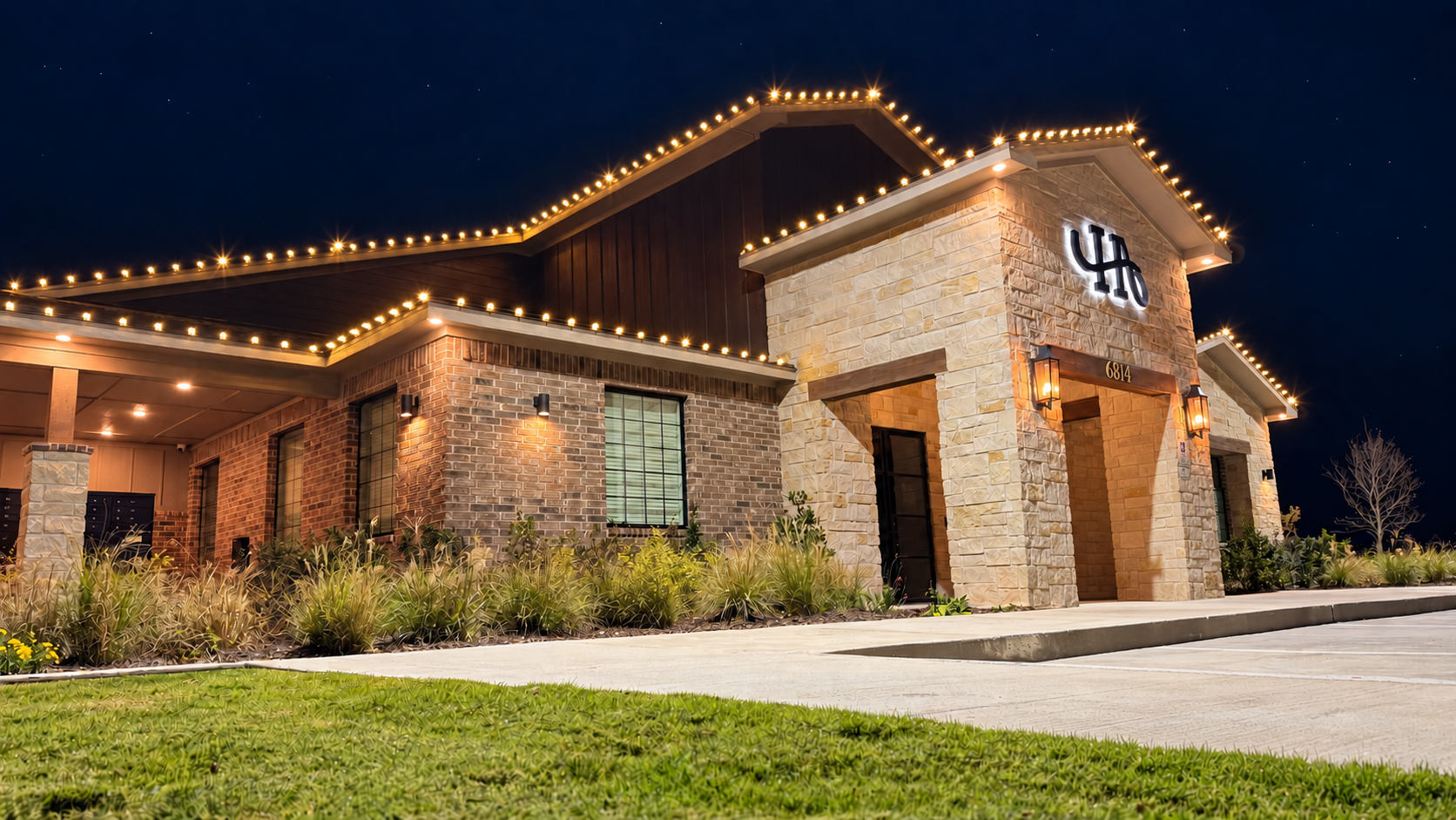 Commercial building decorated with warm white roofline Christmas lights at night